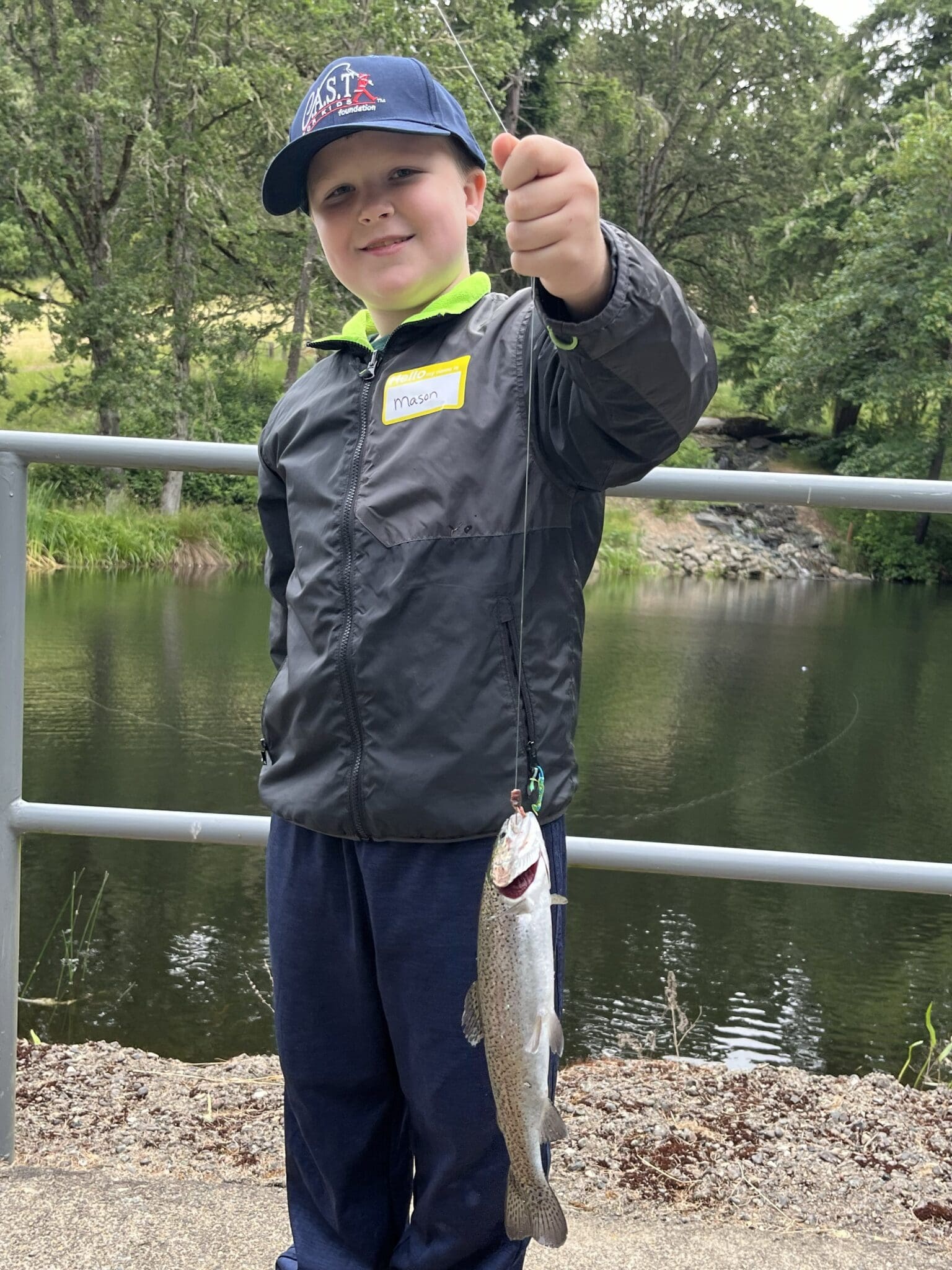 child with blue fishing pole holding fish