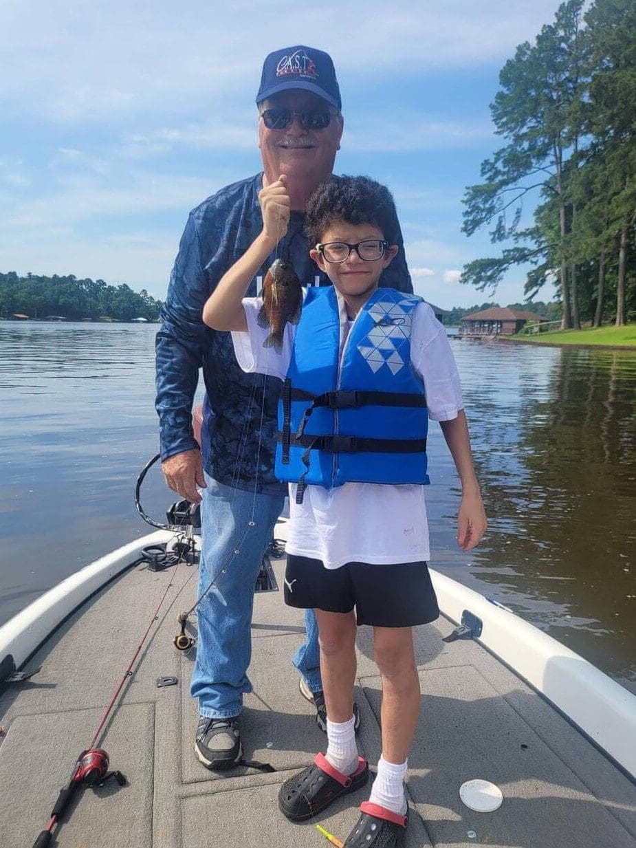 boy holding a fish with a life jacket on