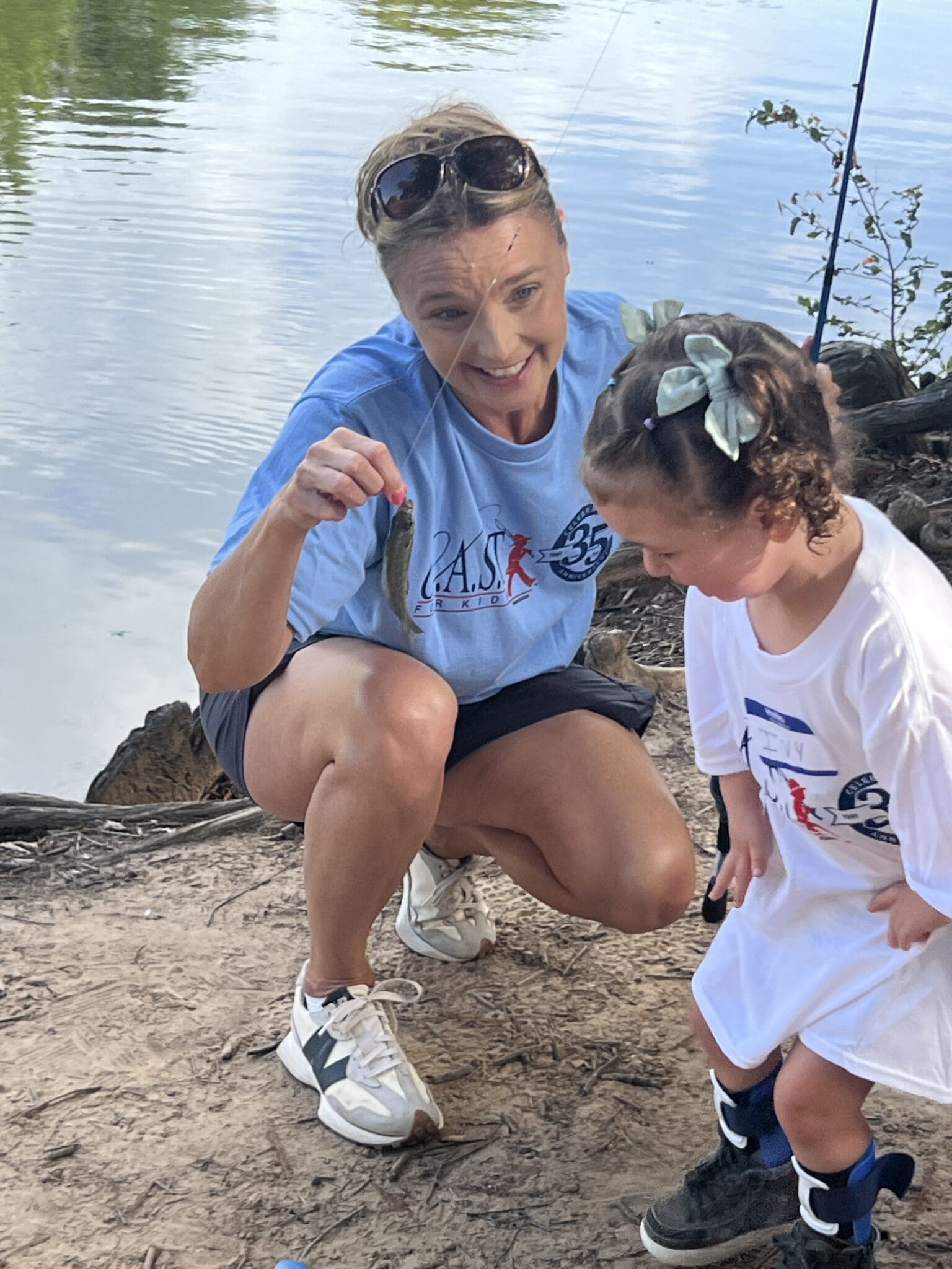 two participants holding fish at central lake pond