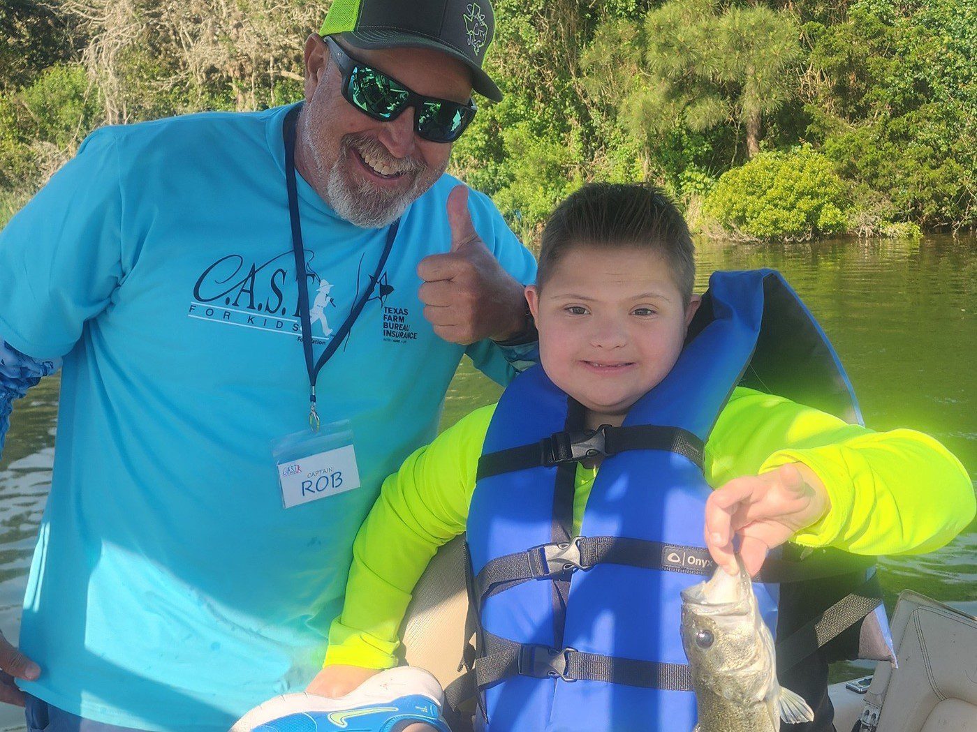 boy holding a fish with a life jacket on