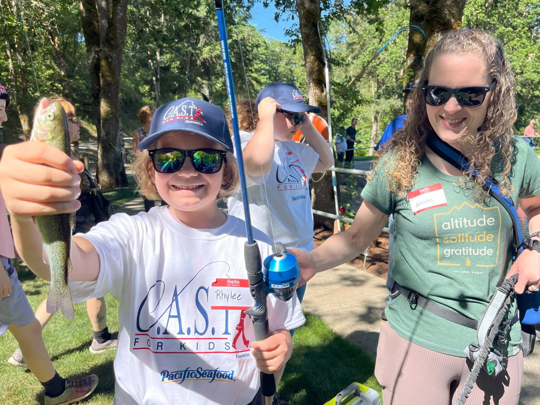 child with blue fishing pole holding fish