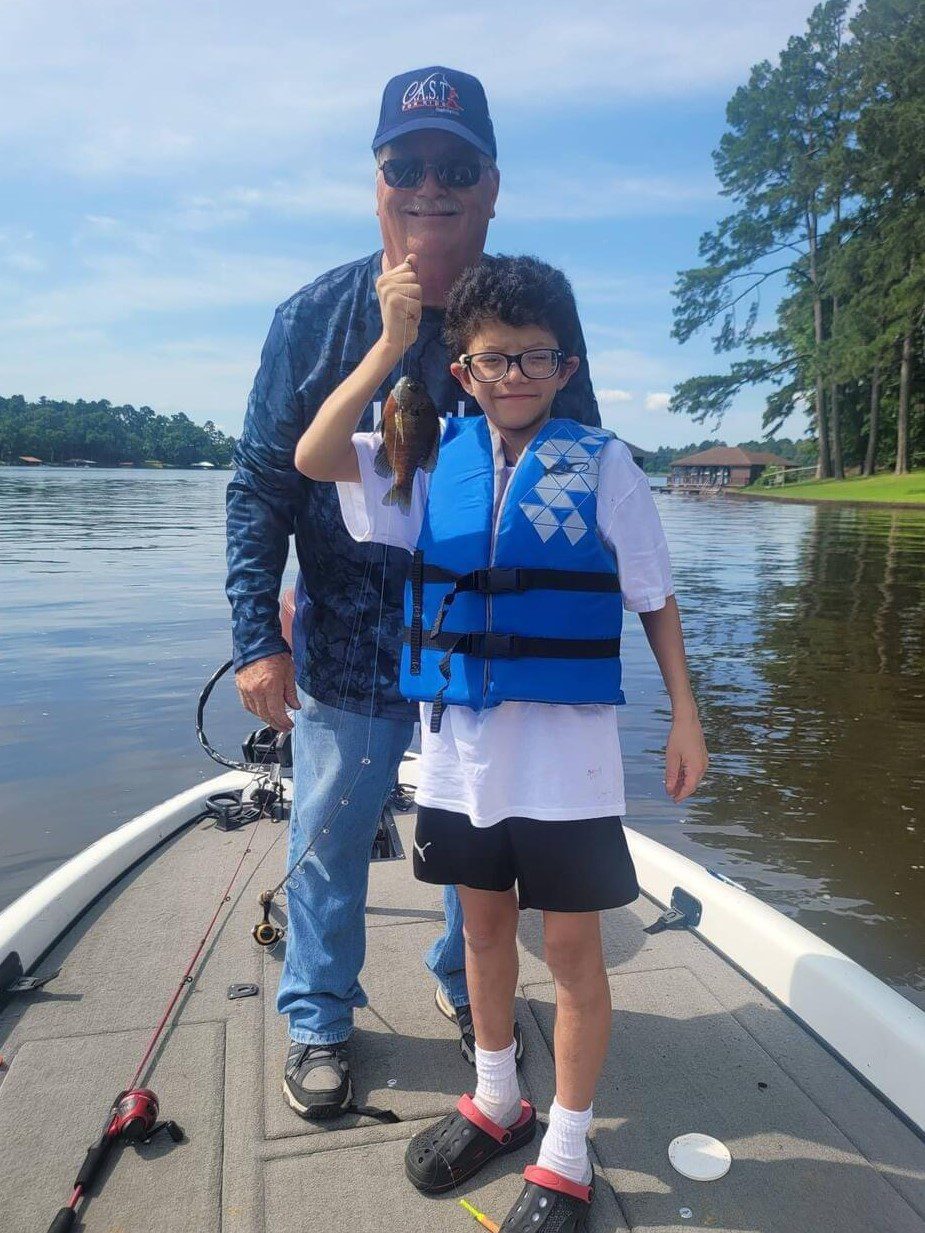 boy holding a fish with a life jacket on