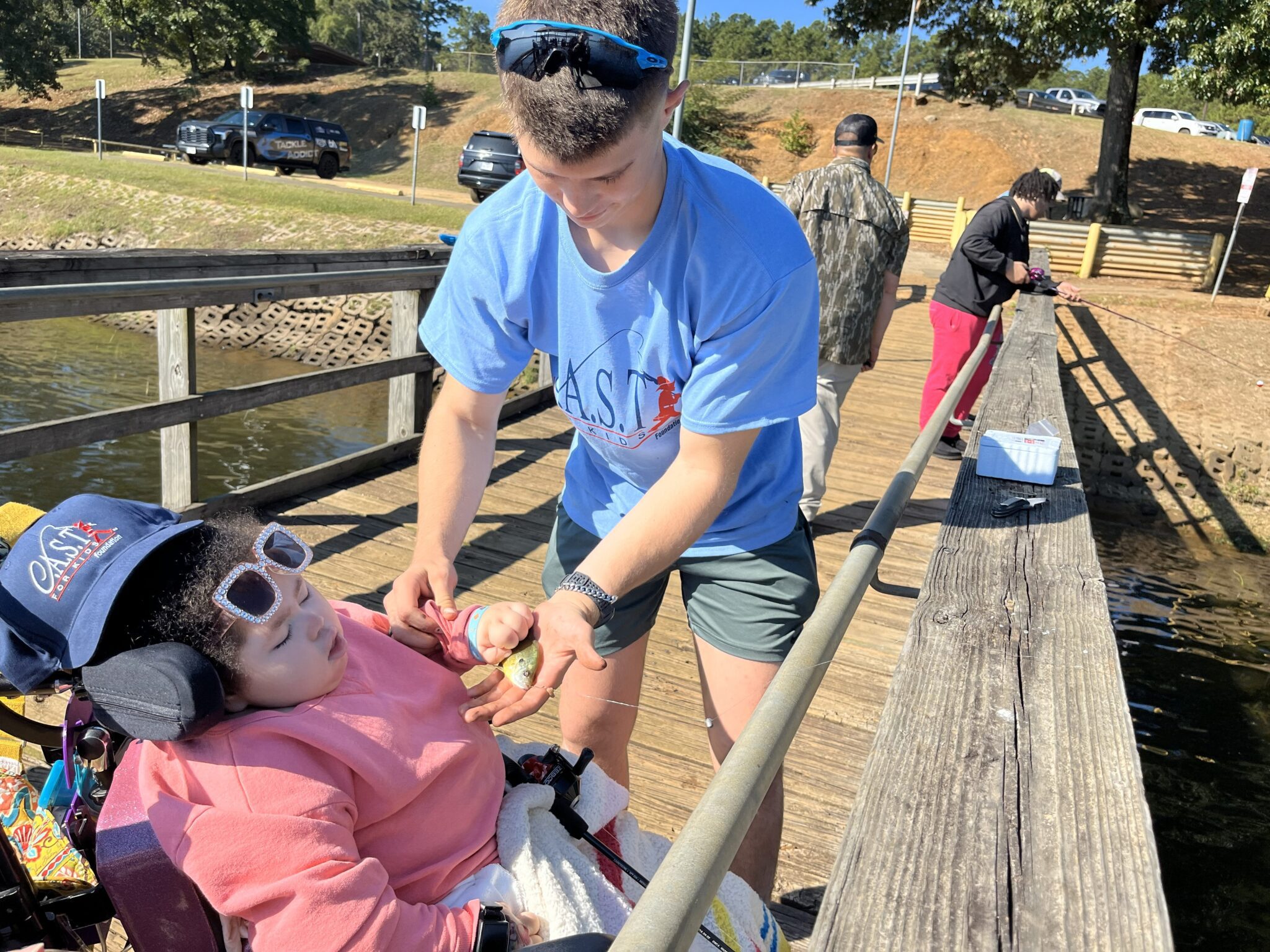 participant holding fish at central lake pond