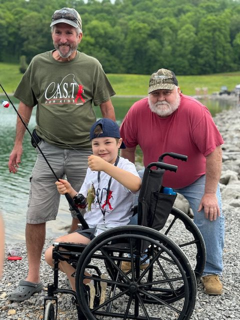 2 male volunteers with a boy fishing