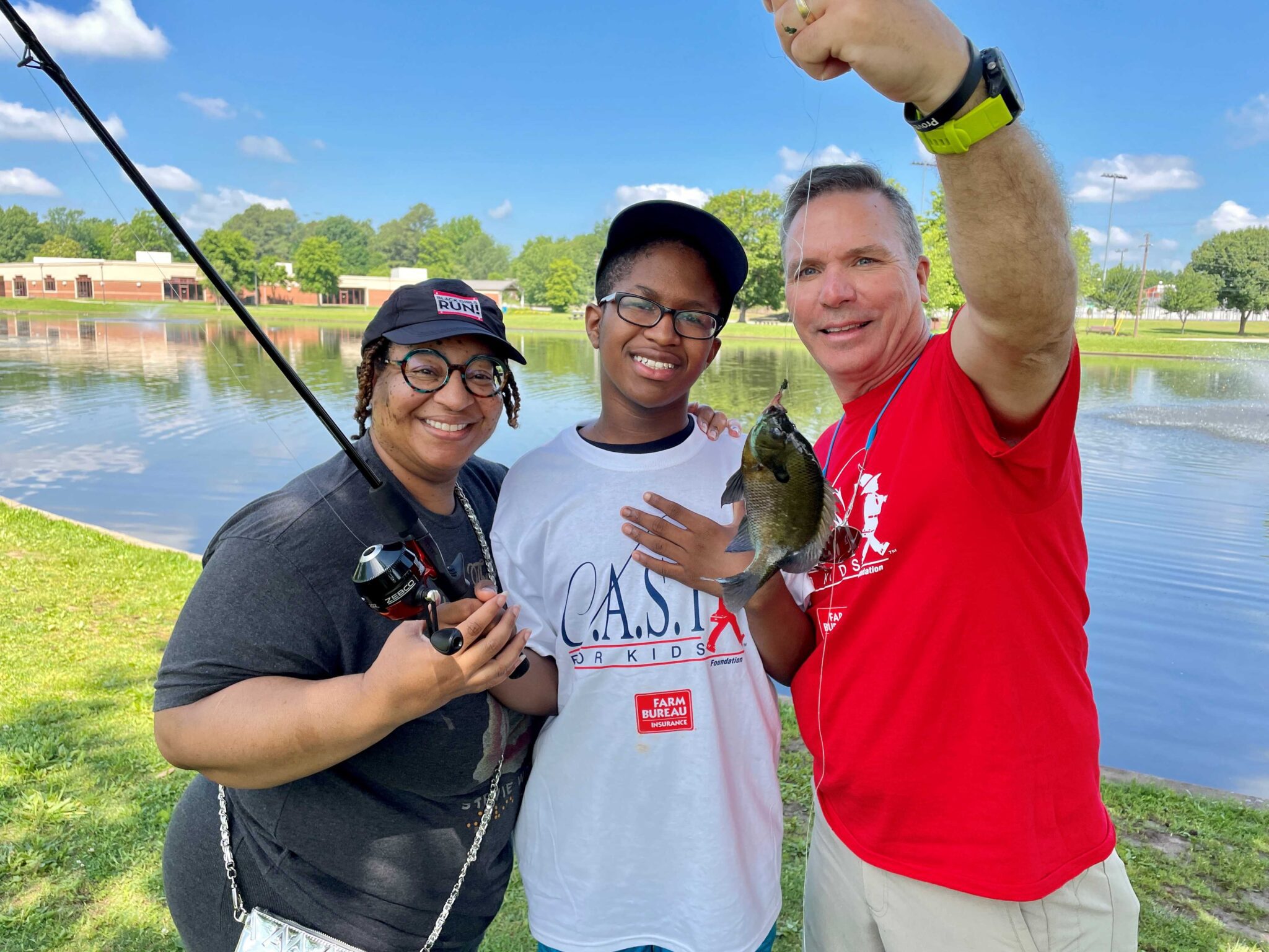 CAST for Kids fishing participant with volunteers holding a fish